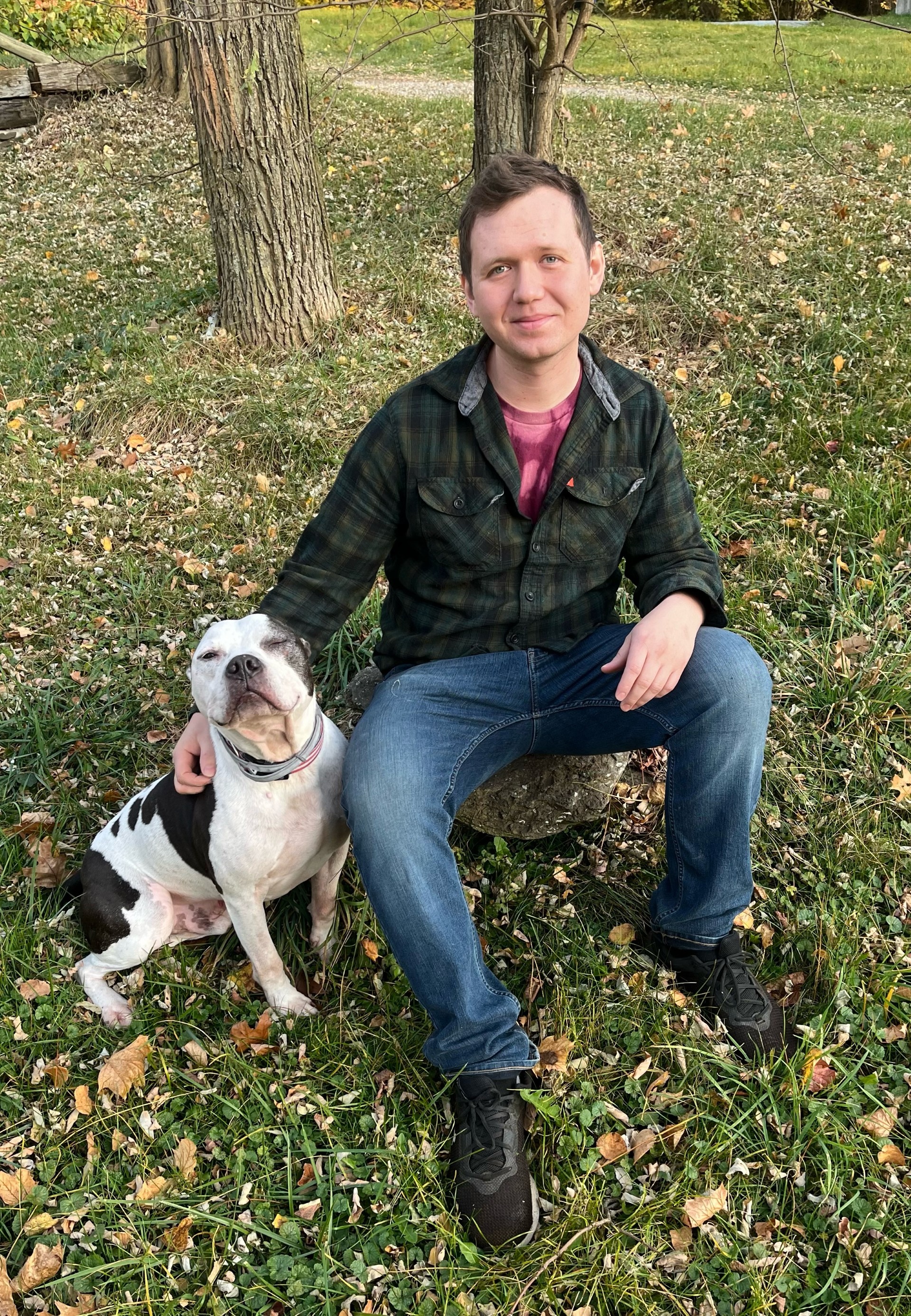 Caleb Carlson sitting outdoors with his dog